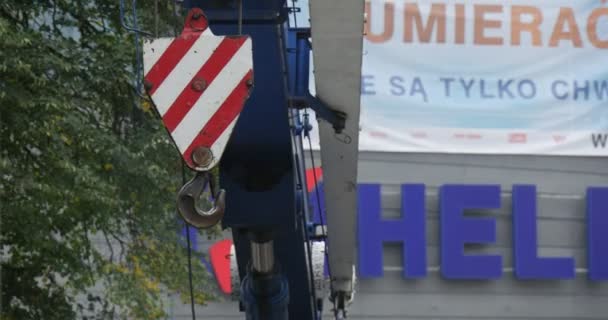 Red and White Hook of Blue Lorry se está levantando con su torre inclinada hacia arriba Camión cargador Reparación de carreteras City Street Inscripción en Polonia en las instalaciones en segundo plano — Vídeo de stock