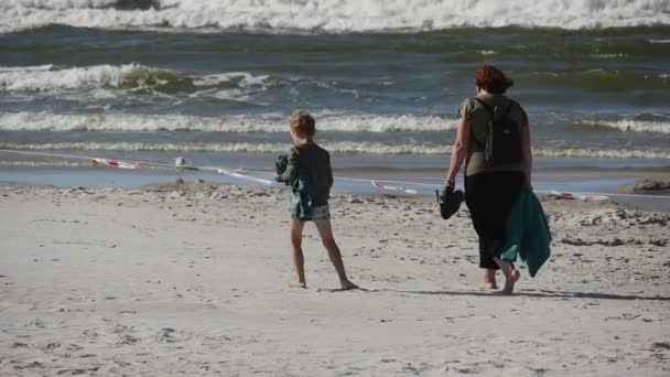 Женщина с маленьким мальчиком - люди, гуляющие на пляже на международном фестивале воздушных змеев в польском городе Фаста . — стоковое видео