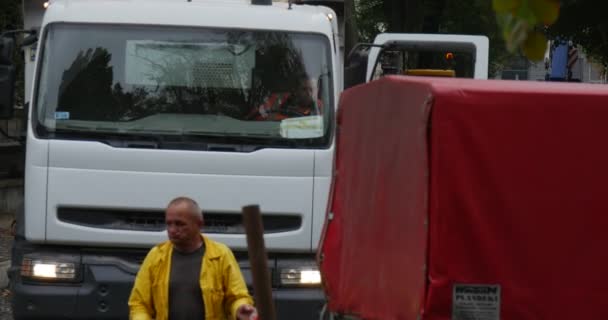 Travailleurs en orange Vêtements de travail Réparation de la route Camion blanc Camion rouge arrive conducteurs Excavatrice jaune avec clignotant Ville Street Trees le long de la rue pavage de la route — Video