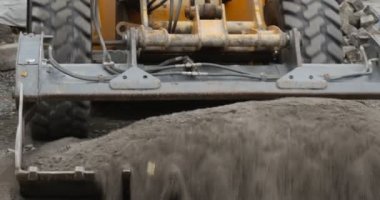 Workers in Orange Workwear Road Repair Yellow Excavator Close Up Scoop Unloads the Granite Dust Heap of Granite Dust Close Up Paving the Road with Blocks