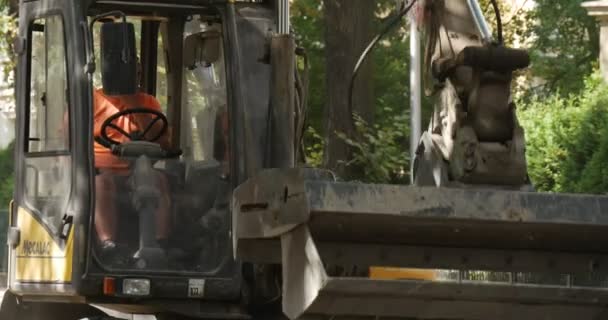 Arbeiders in oranje werkkleding Road Repair Bestrating van de weg met blokken gele graafmachine met Flasher op het dak bestuurder beweegt de Scoop City Street — Stockvideo