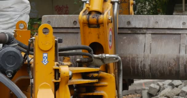 Reparación de carreteras Excavadora amarilla Close Up Scoop Close Up Scoop se mueve pavimentando el camino con bloques de árboles a lo largo de la carretera Paisaje urbano Polonia Opole — Vídeo de stock