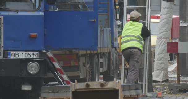 Worker in Workwear is Standing Blue Lorry Transports The Blocks Road Repair Paving the Road with Blocks Trees Rolled with Polietilen Outdoors — Stock videók