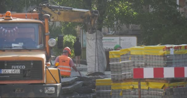 Werknemers in werkkleding op de weg Reparatie Vrachtwagen Graafmachine Achter vrachtwagen Laden van de stukken asfaltpaletten met blokken Wegwijzer Wandelen Mensen Bomen Auto 's — Stockvideo