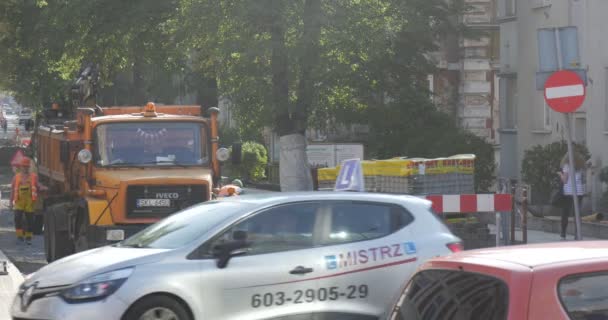 Arbeiter in Arbeitskleidung graben an Straßenreparaturbagger hinter LKW Stadtbild Straßenpaletten mit Straßenschildern Fußgänger Bäume Autos — Stockvideo