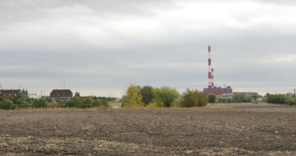 Οικολογία Περιβάλλον ρύπανση ηλεκτρικό σταθμό εργοστάσιο τσιμέντου σε ένα ορίζοντα στο πεδίο επίγειων σπιτιών στέγες κτίρια σωλήνες συννεφιασμένο ουρανό πράσινα δέντρα — Αρχείο Βίντεο