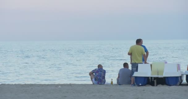 Τέσσερις άνδρες έχουν ένα υπόλοιπο στη θάλασσα, ακτογραμμή, μετά την εργάσιμη ημέρα για καταμαράν, νερό κύκλος, μικρό κορίτσι περνά από — Αρχείο Βίντεο