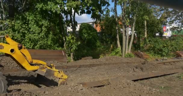 Fahrer in Baggerkabine Arbeiter in orangefarbener Arbeitskleidung gelber Bagger bewegt sich vorwärts und gräbt schwarze Erde aus — Stockvideo