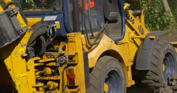 Bestuurder in graafmachine cabine close-up arbeiders in oranje werkkleding gele graafmachine beweegt terug naar voren bewegende voorzijde graven zwarte aarde — Stockvideo