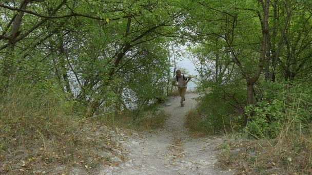 Man Tourist Man s Backballem šplhá nahoru po pěšině na zeleném kopci pomalý pohyb přibližuje se k Předdospělému kopci ve dne venku — Stock video