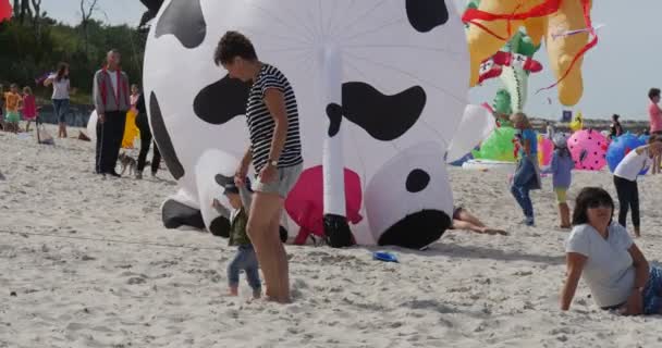 Žena s dítětem na pláži, lidé připravují k vyvěšení jejich draky na mezinárodní Kite Festival v Leba, Polsko — Stock video