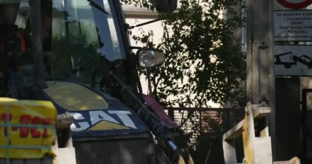 Работники в жёлтой рабочей одежде работают на ремонте дорожного экскаватора CAT крупным планом оставляет водителю поддоны с блоками Sity Street Trees — стоковое видео