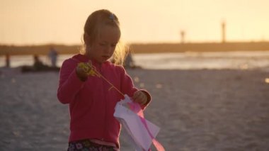 Bir kız küçük bir uçurtma akşam - yürüyüş ya da Uluslararası Uçurtma Şenliği Leba, Polonya sırasında sahilde oturmuş insanlar incelenmesi.