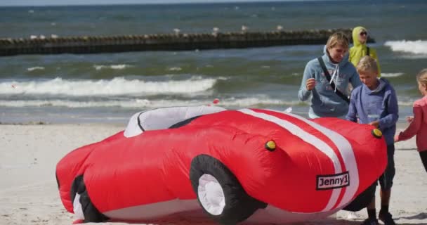 Een rode auto Air zwemmer - mensen voorbereiding van hun vliegers en Air zwemmers starten of vliegen ze op de internationale kite festival in Łeba, Polen. — Stockvideo