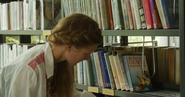 Junge Frau wählt das Buch, das sie nimmt ein Buch und blättert darin Bücherregale Reihen von Büchern drinnen john paul ii Stadtbücherei in Opole Polen — Stockvideo