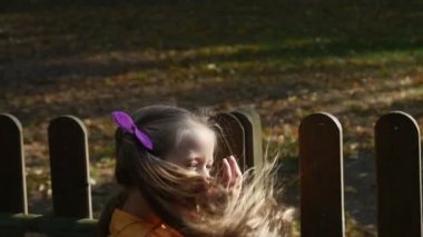 Kız uzun adil tüyleri tırmanmaya ahşap çit cant tırmanmak Going Down ve yürümek uzağa ne yazık ki kızın yüzüne yakın kadar yavaş hareket yeşil Bush üzerinde çalışıyorum olduğunu