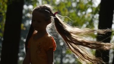 Kız dönüm, Sun gülümseyen ağır çekim küçük kız ile uzun adil tüyleri iki Ponytails leylak yay T-Shirt kıza Bahçesi Tilt aşağı civarındadır