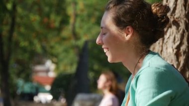 Kadın anne Bank kadın üzerinde oturan küçük kız gülümseyerek top oynamak Her anne Park ağaç çit ile arka plan güneşli günde olmasıdır