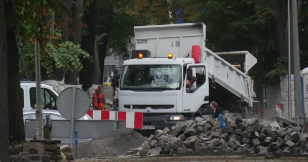 Witte Truck vrachtwagen lost de Heap blokken van blokken Flashers op de vrachtwagen dak werknemers van Oranje werkkleding weg reparatie effenen de weg met blokken stad — Stockvideo