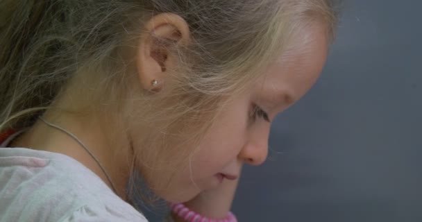 Menina Face Close Up Tilt para baixo imagem Pequena menina loira está pintando o quadro Esculpido Billet da Catedral polonesa — Vídeo de Stock