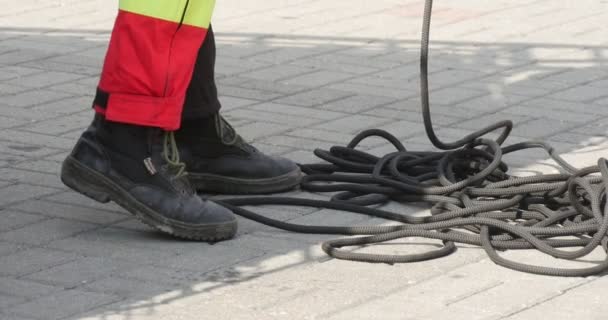 Пожежник тягне ноги чоловіка в чоботях крупним планом чоловік в робочому одязі і шоломі проводять тренування порятунку дітей від високих будівель — стокове відео