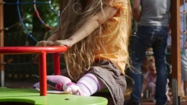 Kız Oyun Alanı'nda Turuncu T-Shirt Uzun Adil Hairs ile Bir Swing Little Girl Üzerinde Onun Oyuncak Tavşan Pembe Tilda Sallanan bir Salıncak üzerinde Sallanan olduğunu