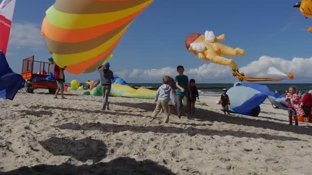 Kinderen duwen een kleurrijke Conic lucht zwemmer in de lucht, proberen om het vangen de wind tijdens de International Kite Festival in Leba, Polen. — Stockvideo