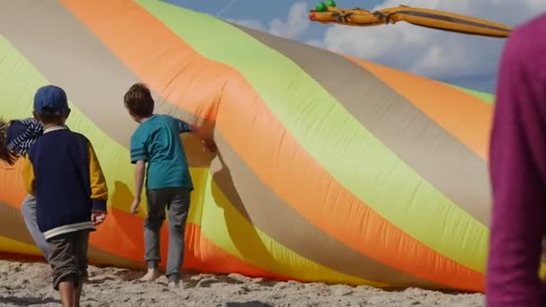 Kinder, die während des internationalen Drachenfestivals in leba, Polen, einen bunten konischen Luftschwimmer in die Luft stoßen und versuchen, ihn zum Fliegen zu bringen. — Stockvideo