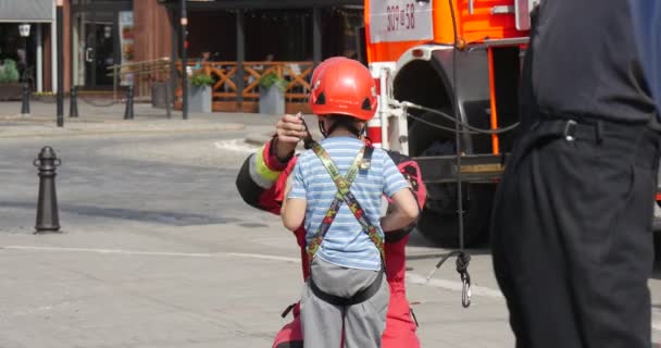 消防员是头盔，系绳儿童打扮孩子爬上绳子楼梯人在工作服和头盔举行训练走路人 — 图库视频影像