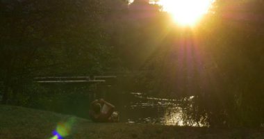 Adam Lake Bank Sırt Çantası oturuyor Yakın Adam Çim Güneş Üzerinde Yatıyor Ağaçlar Siluetler Meadow Arkasında Kamera Güneş parlar