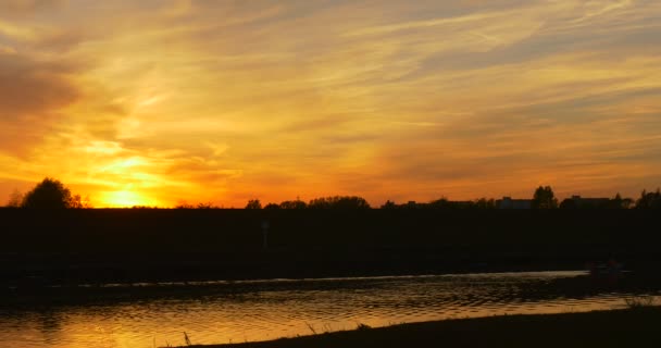 Flux d'eau de la rivière Coucher de soleil jaune vif sur la rivière Nuages colorés Silhouettes des cirrus Crépuscules du soir de l'horizon de rive opposé — Video