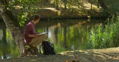Laptop ile Gözlük Man River Freelance Programcı Copywriter Tasarımcı Accauntant De Ağaç Gövde üzerinde Oturuyor River Görünüyor Ducks Çalışmaya Devam