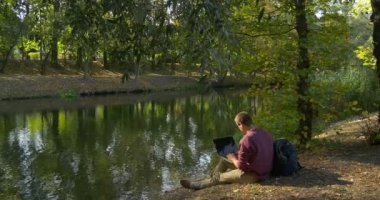 Gözlük Man Laptop Freelance Programcı Tasarımcı Copywriter Muhasebeci ile Çalışıyor River Bank Oturarak Away Laptop Goes Away koyun