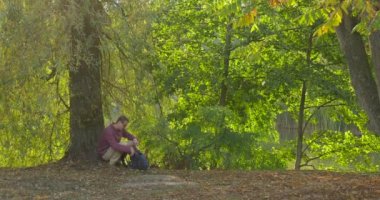 Sırt Çantası ile Man Comes And Oturur Ağaç Freelance Programcı Tasarımcı Copywriter Muhasebeci Kapalı Aldı Laptop Working Man Bisiklet tarafından Sürme