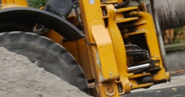 Yellow Excavator is Moving Driver's Leg Excavator Close Up Tracking Left Camera is Following the Machine Pieces of Concrete Road Repair Safety Fence