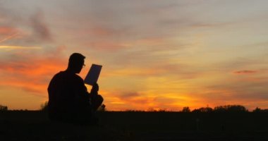 Laptop Freelance Programcı Tasarımcı Serbest Muhasebeci Man's Siluet ile Man Kağıt bakarak Sahada Yerde Oturuyor