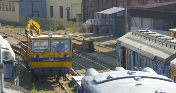 Gelbe Lokomotive mit Eisenbahnschwellen Kran mit Haken Arbeiter in orangefarbener Arbeitskleidung entladen das Metalldetail Mann raucht Opole Poland sonnig — Stockvideo