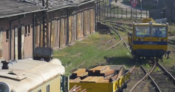 黄色の機関車は枕木と移動の方のカメラのドライバーのシルエット Platphorm 立って駅建物日当たりの良い日オポーレです。 — ストック動画