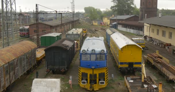 Áruszállító vonatok a vasúti vasúti állomás első Windows épület tornyok vezetékek felhős Időjárás szürke ég a zöld fák a horizont alá Opolskie Lengyelország — Stock videók