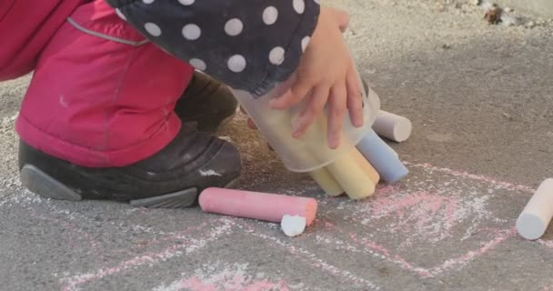 Little Girl Hands Close Up tira os giz do balde e colocá-los novamente Menina em jaqueta em bolinhas Botas imagem no inverno asfalto — Vídeo de Stock