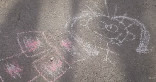 Cuadro pintado en el asfalto por el niño pequeño pintado por tiza colorida Imagen de la niña sonriente humana Día soleado al aire libre — Vídeos de Stock