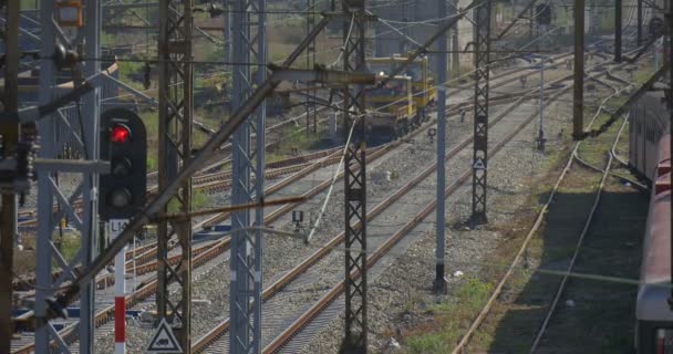 Locomotiva gialla si sta allontanando da Raildoad, treni vagoni stazione ferroviaria stazione ferroviaria giunzione ferrovia semafori rosso filo torri — Video Stock