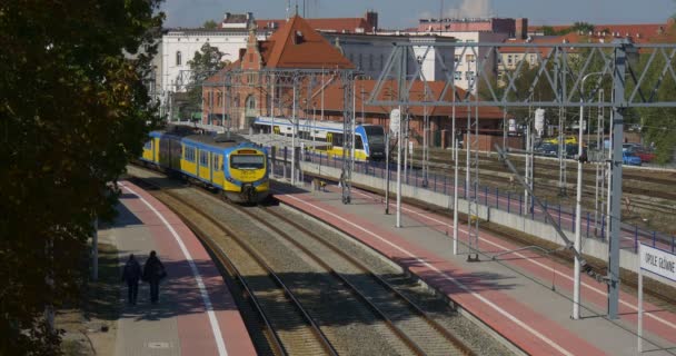 Dos personas Pasajeros están despertando a lo largo del ferrocarril Trenes de pasajeros Vagones Estación de ferrocarril Estación de ferrocarril Enlace ferroviario Torres de alambre — Vídeos de Stock