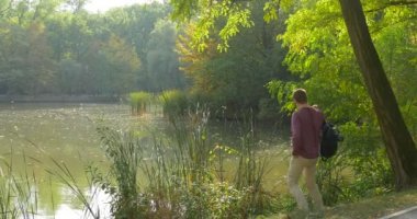 Adam göl yerine bir süre ve suya bakmak ve onun kafa yeşil akasya dalları Reed geri çeviriyor yürüme için ayakta üzerinde sırt çantasını, gözlük