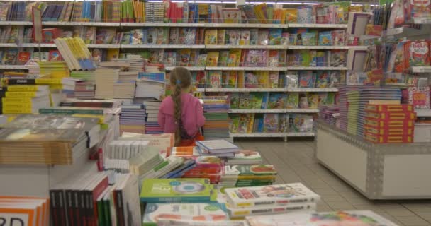 Девочка в супермаркете выбирает книгу, переворачивая страницы — стоковое видео