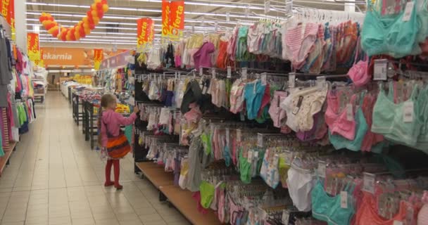 Niña en ropa interior del Departamento Grande. Poco a poco se mueve entre los estantes, tocando cosas y mirando el precio Etiquetas . — Vídeos de Stock