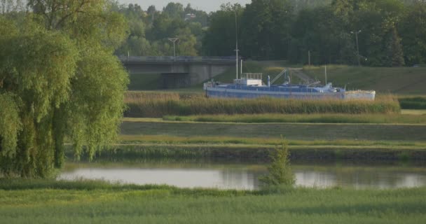 Skepp, båt stående i kanalen, kanal nära äng och bro — Stockvideo