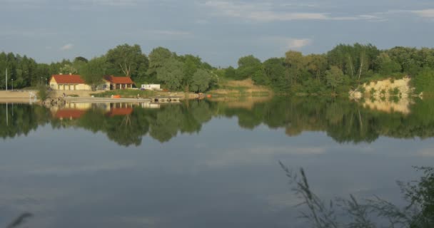 Дома, здания, коричневые крыши, на берегу гладкого пруда, озера, реки — стоковое видео