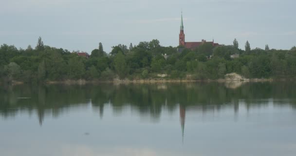 Bank of Pond, Lake, River, Green Trees And Red Buildings, Steeple. Reflection in the Water, Summer Day, Blue Sky.Water on foreground — Stock Video