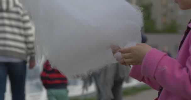 Menina loira de blusa rosa está comendo algodão doce, verão, ao ar livre — Vídeo de Stock
